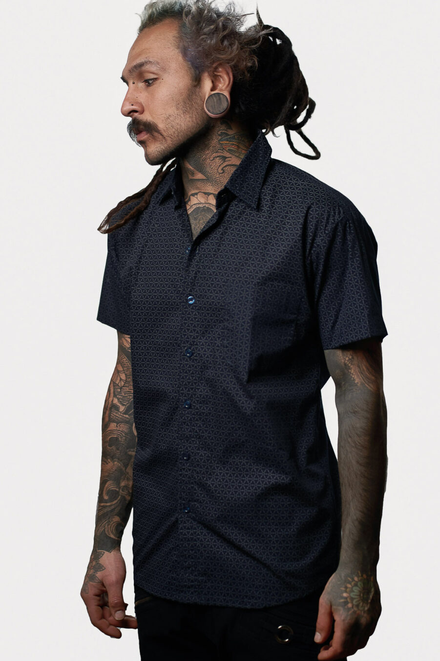 The Flower of Life dark blue button-up shirt for men, featured in Avanyah's online shop, stands out with its unique screen-printed pattern. A fusion of alternative fashion and festival outfits, it's a wearable art piece for the discerning gentleman.